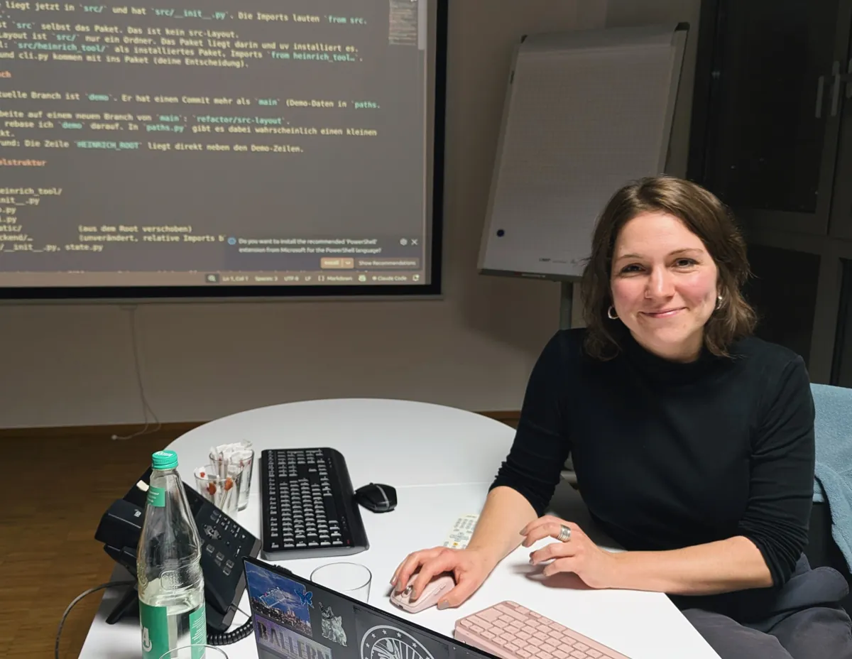 Pauline am Konferenztisch, hinter ihr auf der Leinwand der Plan für den Umbau auf das src-Layout